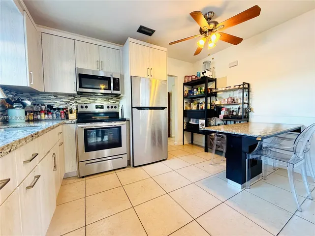 a kitchen with stainless steel appliances kitchen island granite countertop a refrigerator and a stove top oven