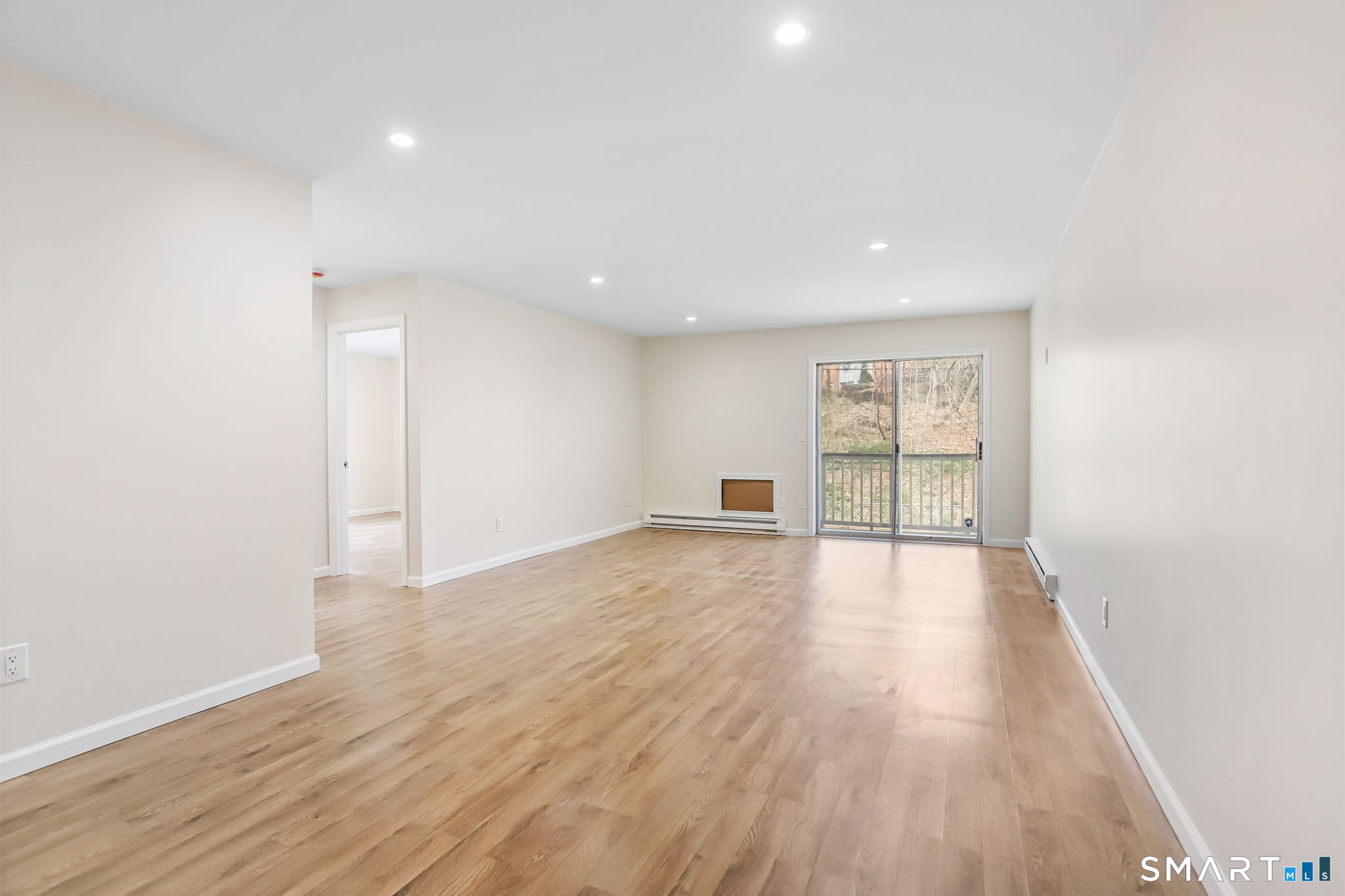 a view of an empty room with wooden floor and a window