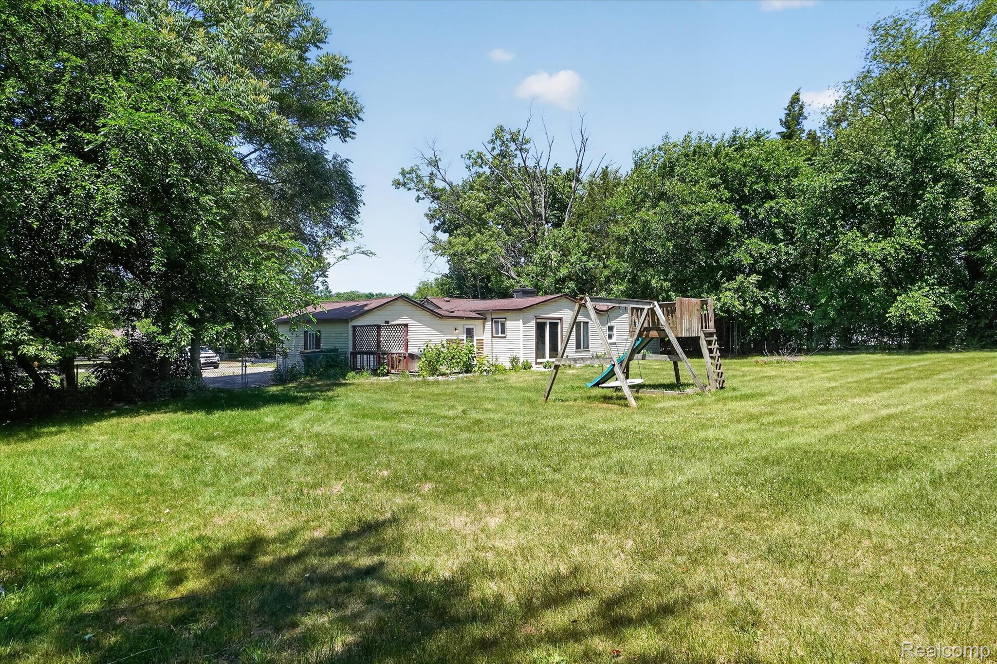 508 Deland Road Flushing, MI 48433 - Photo 28 of 38 Expansive green lawn surrounds the property, featuring mature trees and a swing set