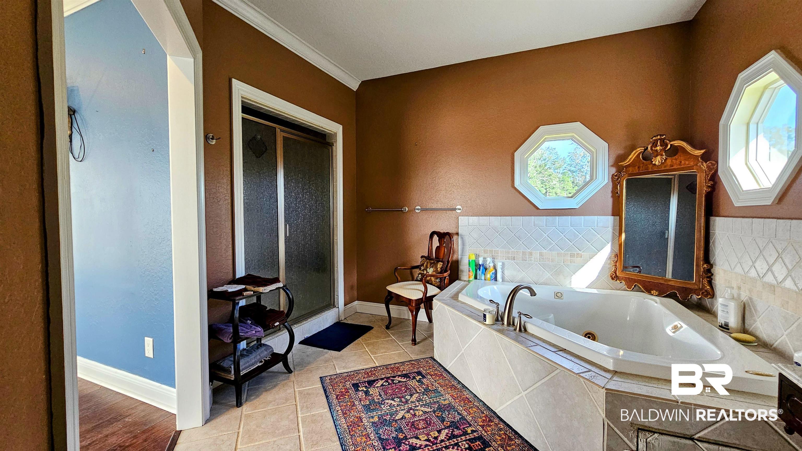 9275 Crawford Road Elberta, AL 36530 - Photo 15 of 28 Bathroom featuring a tub with jets, light tile patterned floors, a shower stall, and ornamental molding