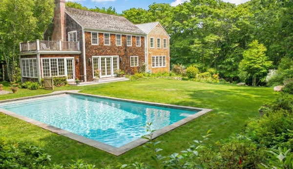 a view of swimming pool with lawn chairs and plants