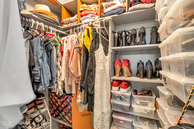 a view of walk in closet with clothes and shoes
