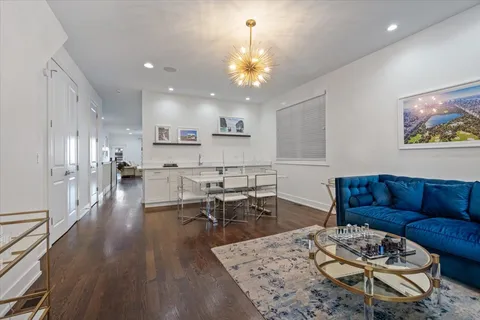 a living room with furniture kitchen view and a chandelier