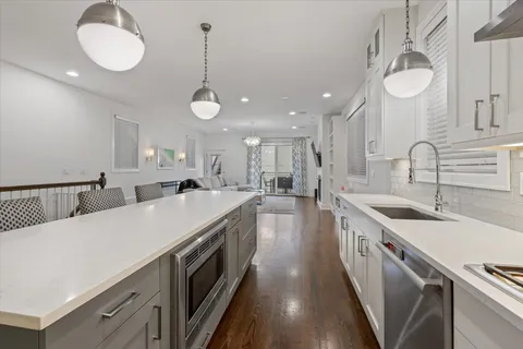 a large kitchen with kitchen island a stove a sink a chimney and cabinets