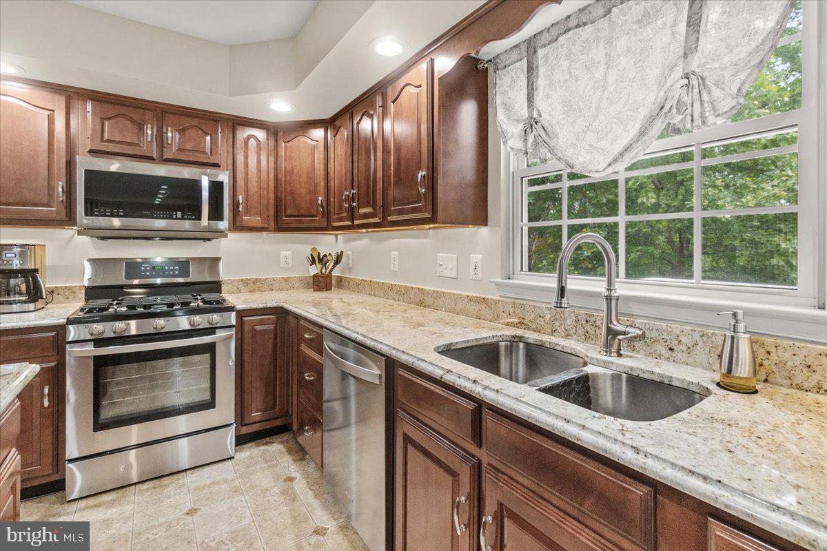 2218 West Greenleaf Drive Frederick, MD 21702 - Photo 13 of 46 a kitchen with stainless steel appliances granite countertop a sink a stove a microwave and wooden cabinets
