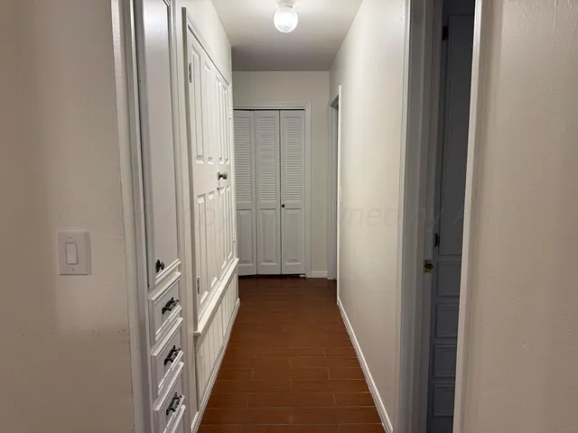 a view of a hallway with wooden floor and a bathroom