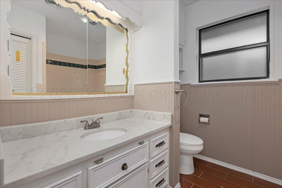 7606 Canode Drive Amarillo, TX 79121 - Photo 24 of 30 a bathroom with a granite countertop sink a toilet and a mirror
