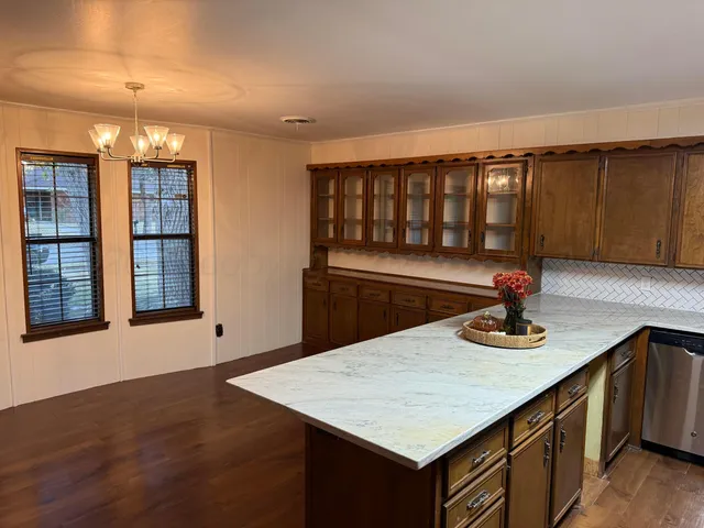 a kitchen with stainless steel appliances granite countertop a sink dishwasher and cabinets with wooden floor