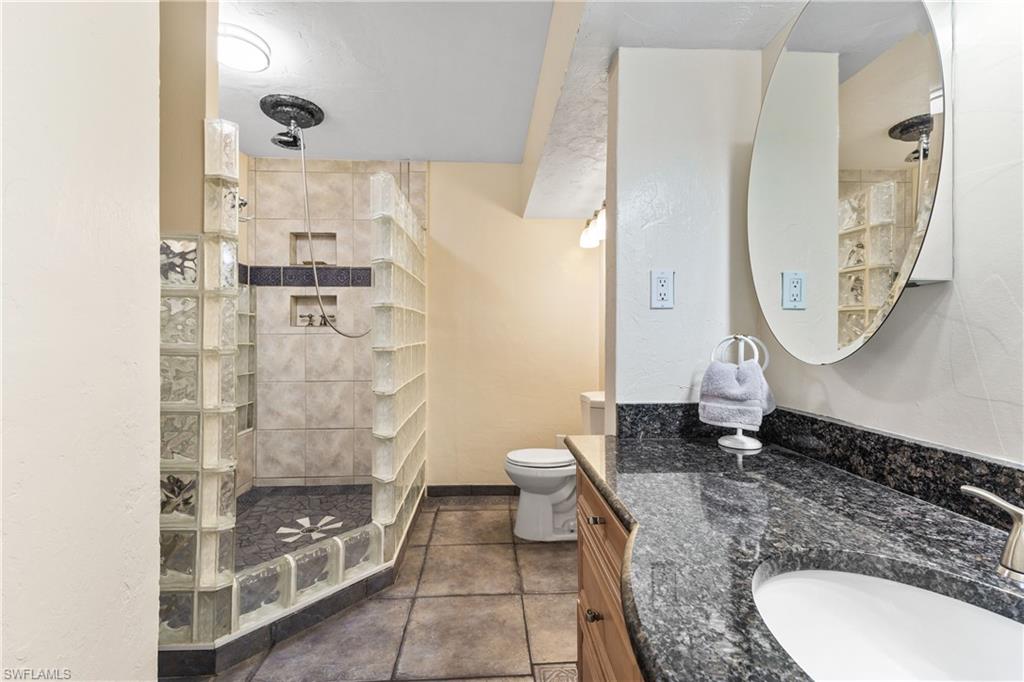 8012 Kansas Road Fort Myers, FL 33967 - Photo 18 of 44 Bathroom with tiled shower, tile patterned flooring, toilet, and vanity