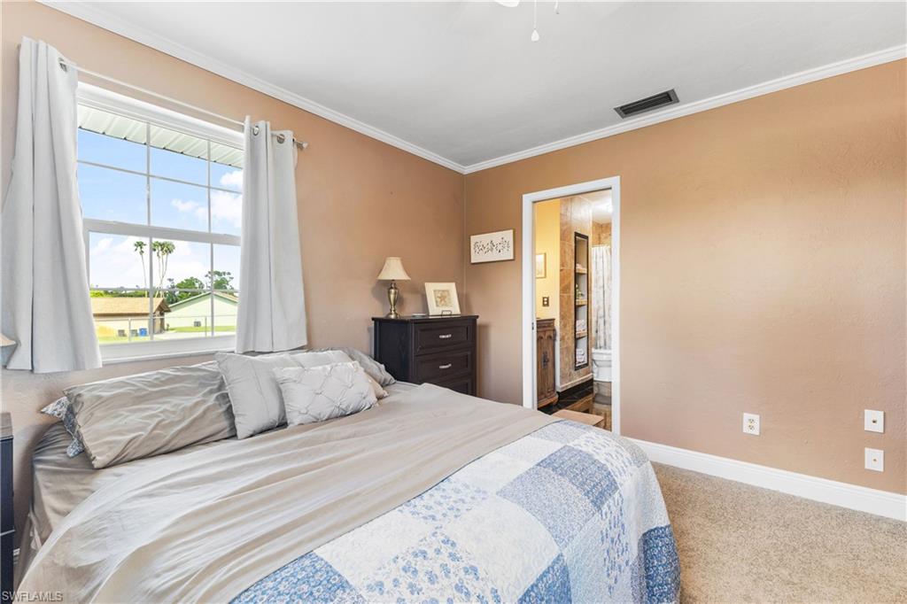 8012 Kansas Road Fort Myers, FL 33967 - Photo 29 of 44 Carpeted bedroom with ornamental molding, ensuite bathroom, and ceiling fan