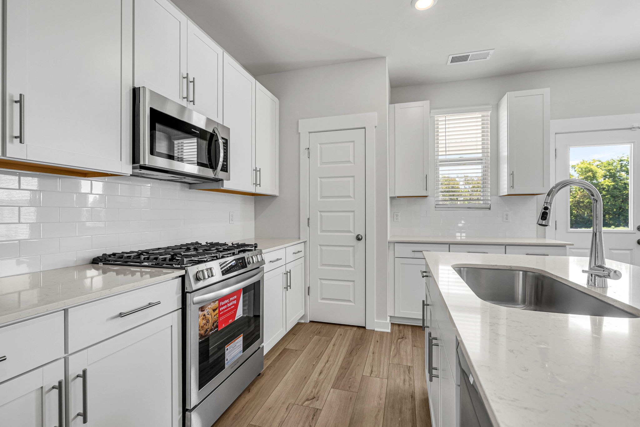 219 Goldfinch Road Mount Juliet, TN 37122 - Photo 10 of 58 a kitchen with stainless steel appliances granite countertop white cabinets a sink dishwasher a stove and a refrigerator with wooden floor