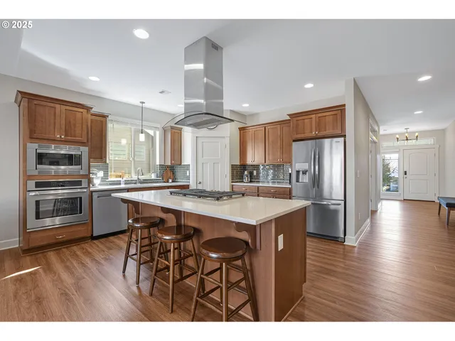 a kitchen with stainless steel appliances a refrigerator a stove a sink cabinets and wooden floor