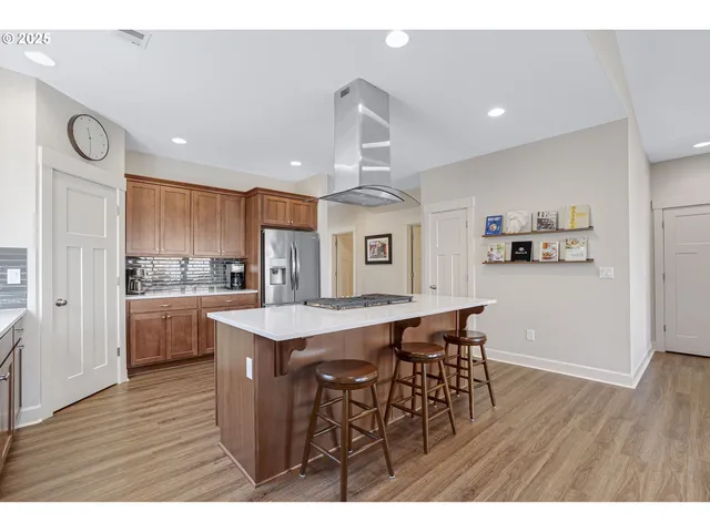 a kitchen with stainless steel appliances granite countertop a wooden table chairs and cabinets