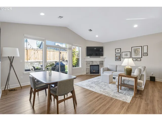 a living room with furniture a fireplace and a dining table with wooden floor