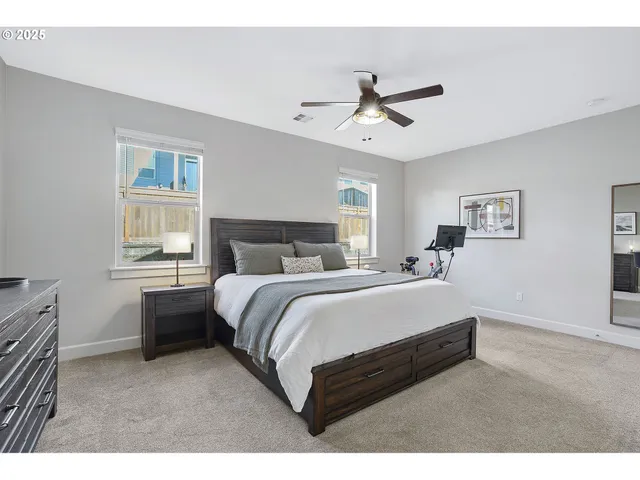a bedroom with a bed painting on wall and two windows