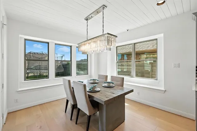 a dining room with wooden floor a chandelier a wooden table and chairs