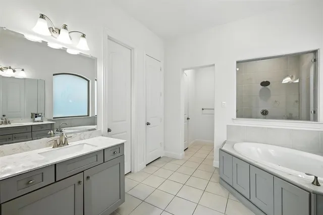 a spacious bathroom with a tub sink and mirror