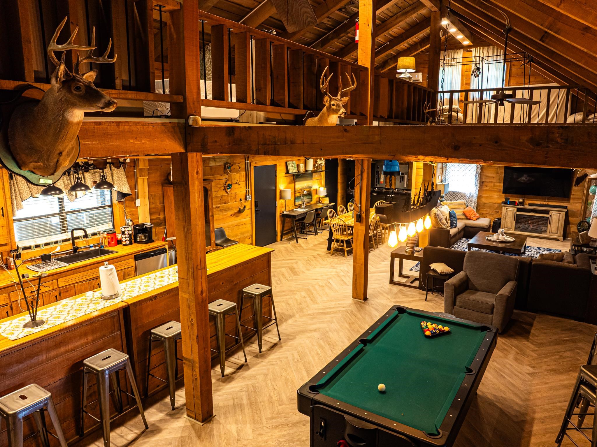 Open-concept living space featuring wood-finish flooring, a full kitchen with a breakfast bar, a separate dining area, a dedicated living room, and a billiards table