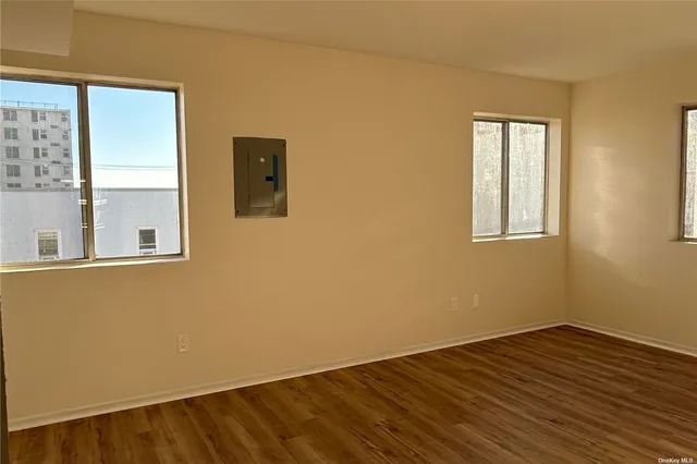 a view of an empty room with wooden floor and a window