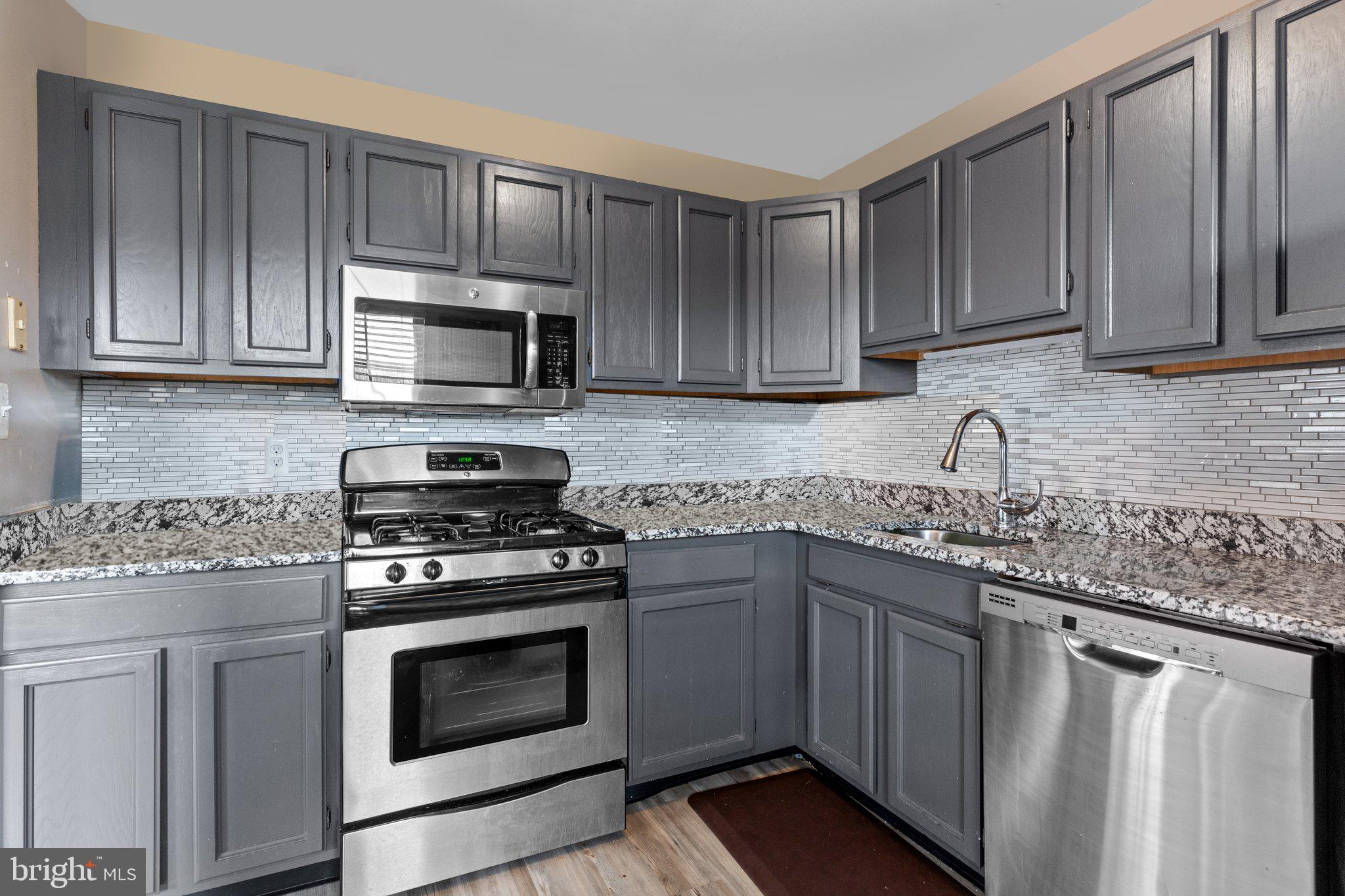 2404 Brookhaven Drive, Unit 330 Yardley, PA 19067 - Photo 9 of 27 a kitchen with granite countertop wooden cabinets and stainless steel appliances