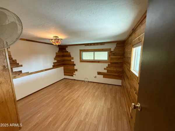 a view of empty room with wooden floor and fan