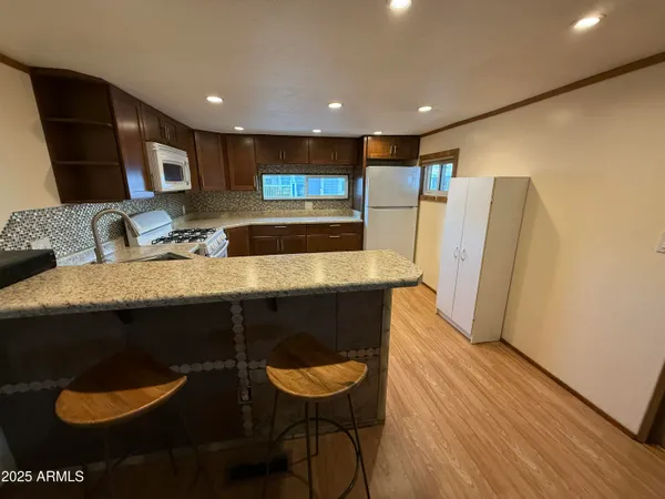 a kitchen with stainless steel appliances granite countertop a refrigerator a sink and wooden floors
