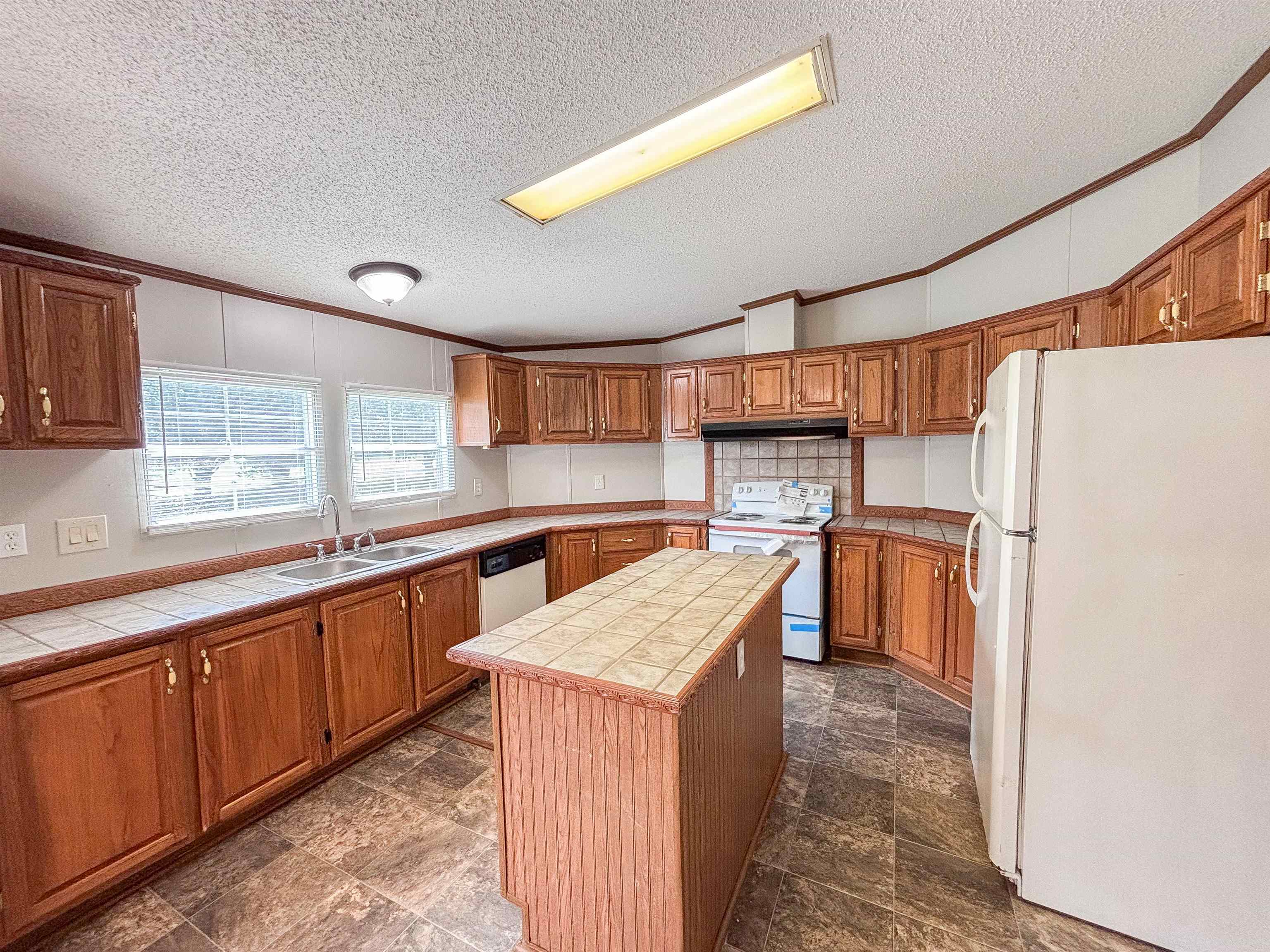 2847 Holly Grove Road Covington, TN 38019 - Photo 11 of 36 Kitchen featuring wood cabinetry, tile countertops, a center island with a tile surface, a double basin sink, and a tile backsplash