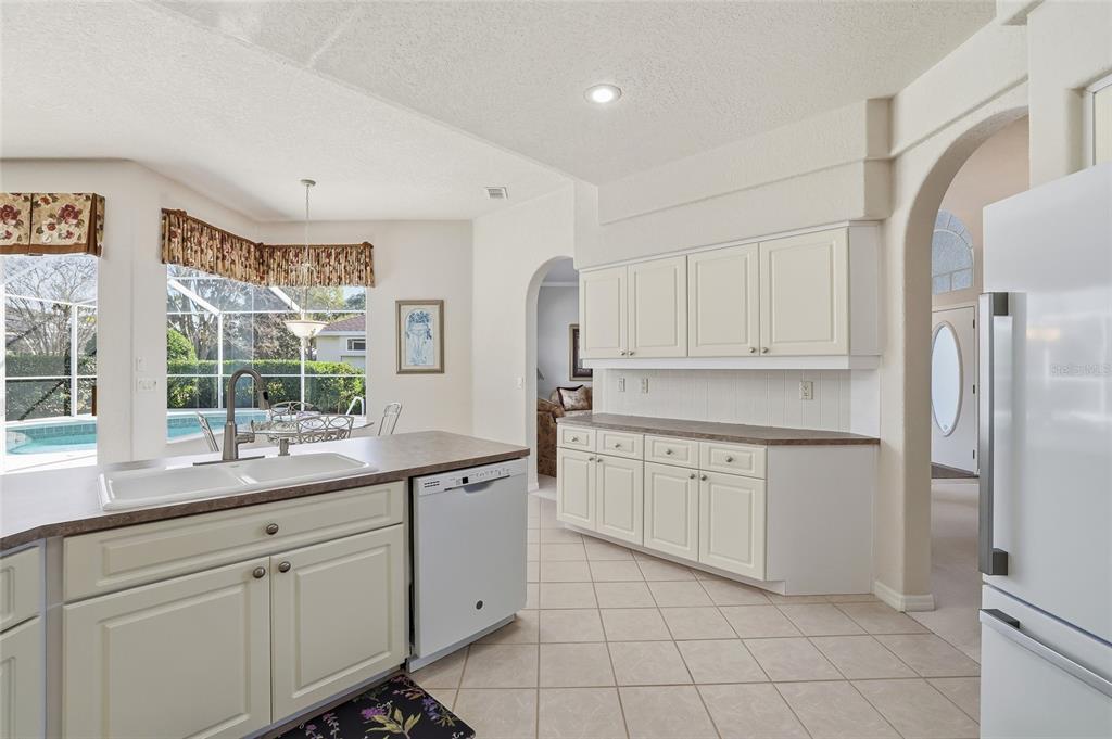 3521 Conifer Loop Spring Hill, FL 34609 - Photo 22 of 71 a kitchen with white cabinets appliances a sink and a large window