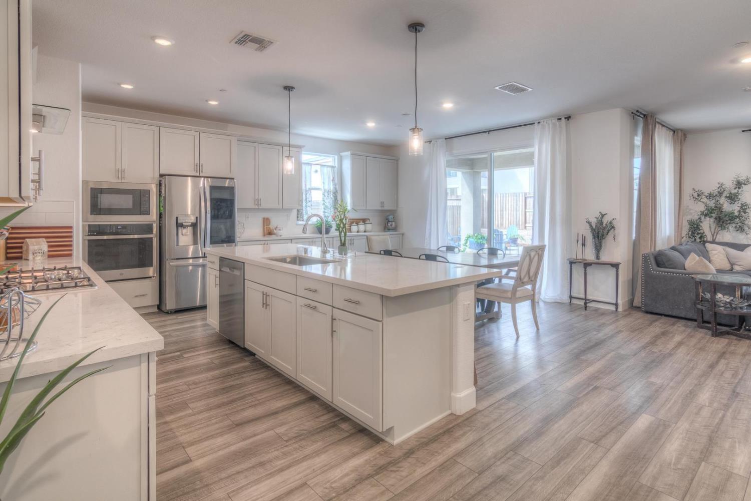 2116 Abbeyhill Road Lincoln, CA 95648 - Photo 7 of 46 a kitchen with stainless steel appliances kitchen island granite countertop a stove a sink a refrigerator and white cabinets with wooden floor