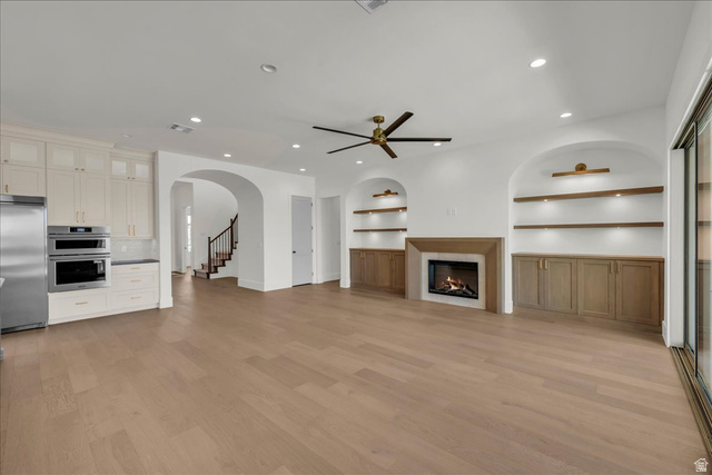 1620 Belayer Drive St. George, UT 84770 - Photo 7 of 51 Spacious living area featuring light wood-finish flooring, a contemporary fireplace, and built-in shelving with integrated lighting