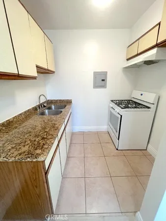 a kitchen with granite countertop a sink stove and cabinets