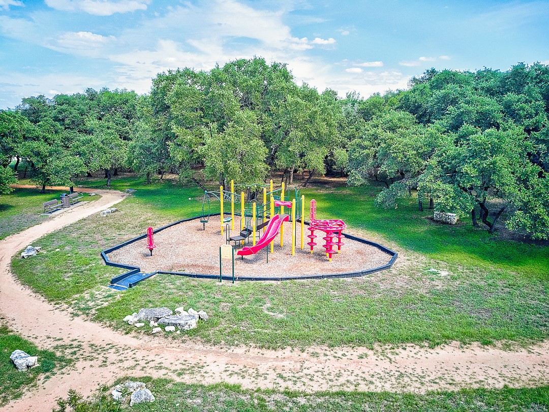 311 A Utterback Kyle, TX 78640 - Photo 37 of 40 Community playground featuring a multi-color play structure with slides and swings, surrounded by woodchip surfacing