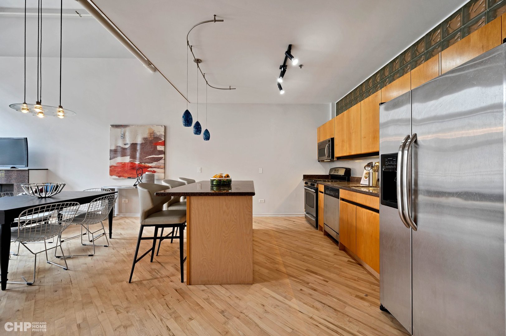 203 South Sangamon Street, Unit 206 Chicago, IL 60607 - Photo 8 of 20 a kitchen with stainless steel appliances kitchen island granite countertop a table chairs in it and wooden floors