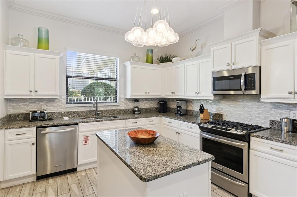 7423 Sparkling Court Reunion, FL 34747 - Photo 19 of 62 a kitchen with granite countertop a sink a stove a microwave and cabinets