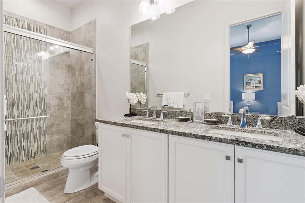 7423 Sparkling Court Reunion, FL 34747 - Photo 23 of 62 a bathroom with a granite countertop sink a toilet and a shower