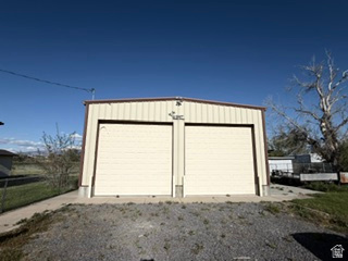 588 North 4500 West West Point, UT 84015 - Photo 42 of 61 Metal-sided outbuilding featuring two large roll-up doors, a concrete pad, and a gravel approach