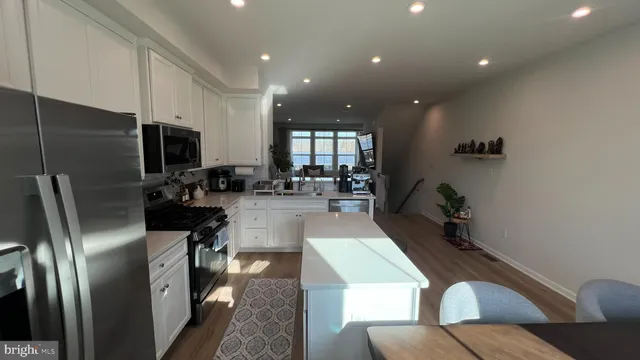 a kitchen with stainless steel appliances granite countertop a refrigerator a sink a stove and a refrigerator with wooden floor