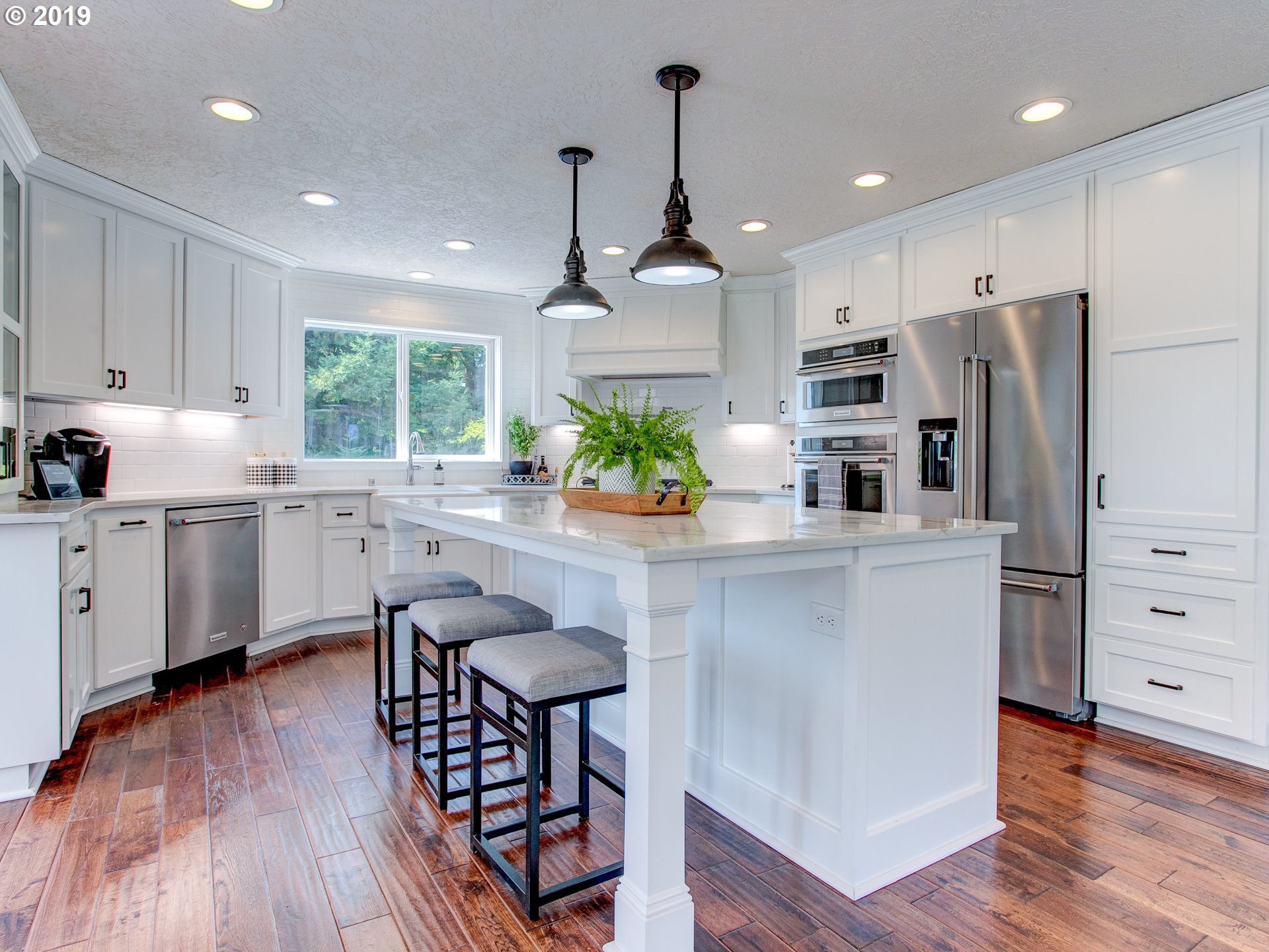 417 Northeast 299th Street Ridgefield, WA 98642 - Photo 17 of 32 a kitchen with stainless steel appliances a center island wooden floor cabinets and a window