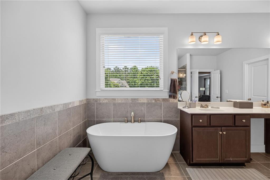 139 Manchester Lane Villa Rica, GA 30180 - Photo 36 of 60 a spacious bathroom with a bathtub a sink and a large mirror
