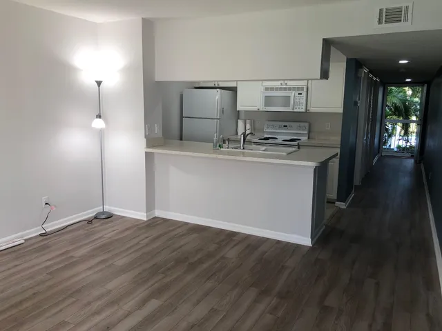 a view of open kitchen with granite countertop cabinets and wooden floor