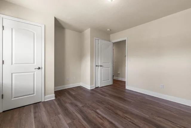 an empty room with wooden floor & closet area