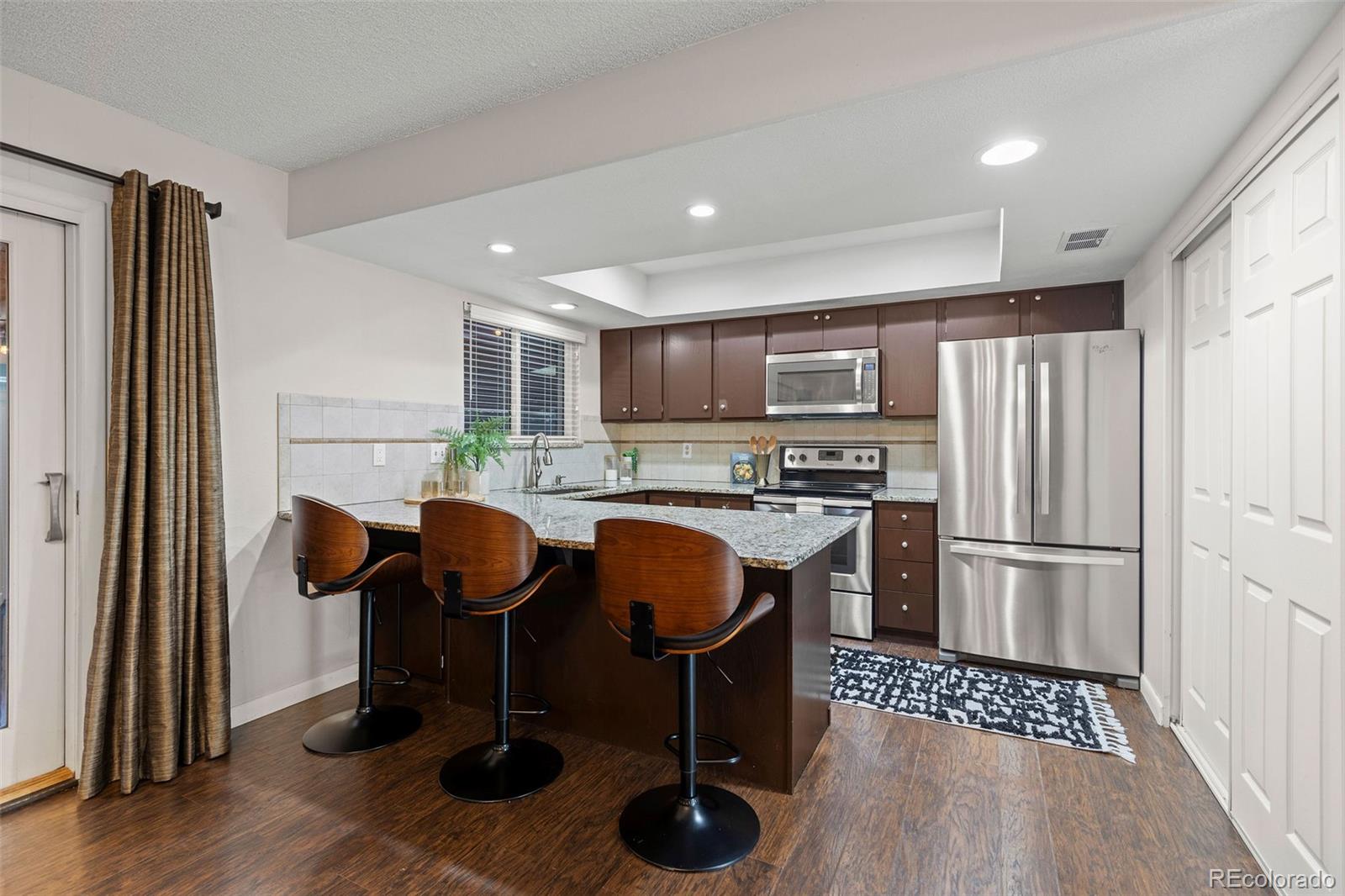 9149 Mansfield Avenue, Unit L Denver, CO 80237 - Photo 11 of 35 a kitchen with stainless steel appliances granite countertop a refrigerator and a stove top oven