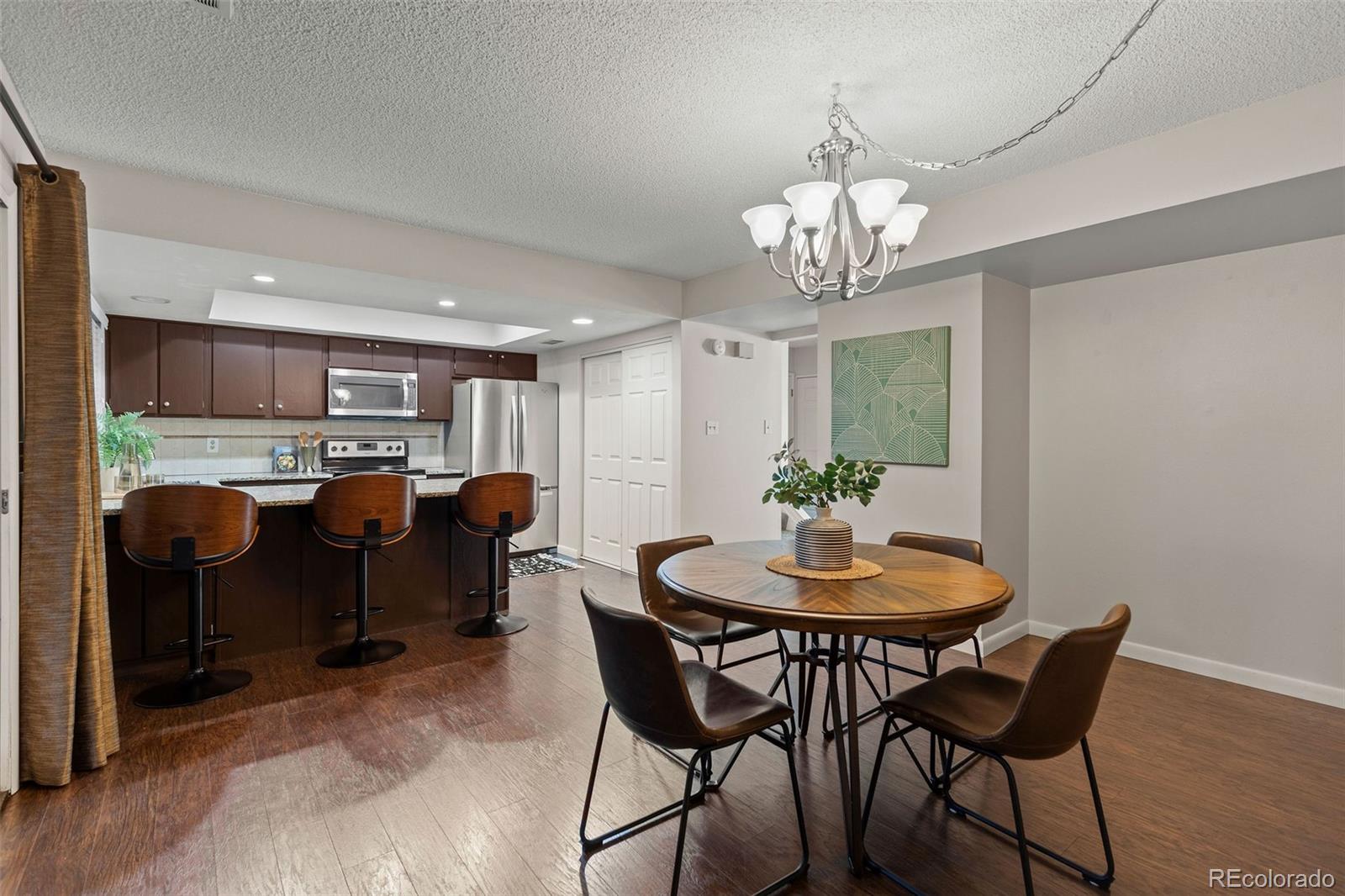 9149 Mansfield Avenue, Unit L Denver, CO 80237 - Photo 13 of 35 a dining room filled chandelier and kitchen view