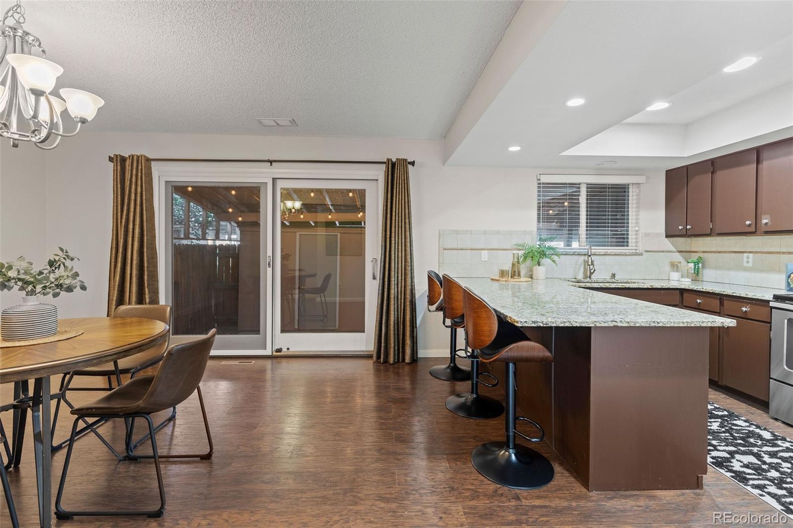 9149 Mansfield Avenue, Unit L Denver, CO 80237 - Photo 10 of 35 a kitchen with stainless steel appliances granite countertop a table chairs sink and cabinets