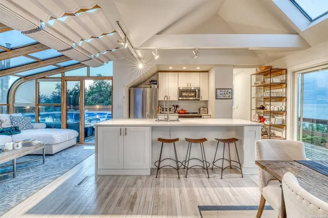 a dining hall with stainless steel appliances kitchen island granite countertop a table chairs and a large window