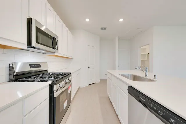 a large white kitchen with a sink and a large mirror with a washer dryer