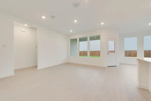 a view of kitchen with kitchen island a sink a stove a refrigerator and white cabinets
