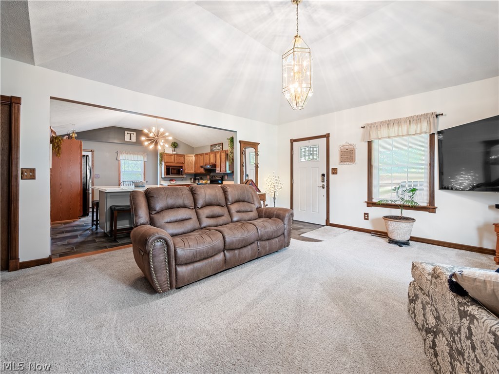 5245 Center Road Philo, OH 43771 - Photo 11 of 39 Carpeted living room featuring a notable chandelier and vaulted ceiling