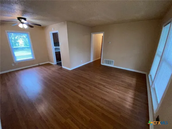 an empty room with wooden floor and windows