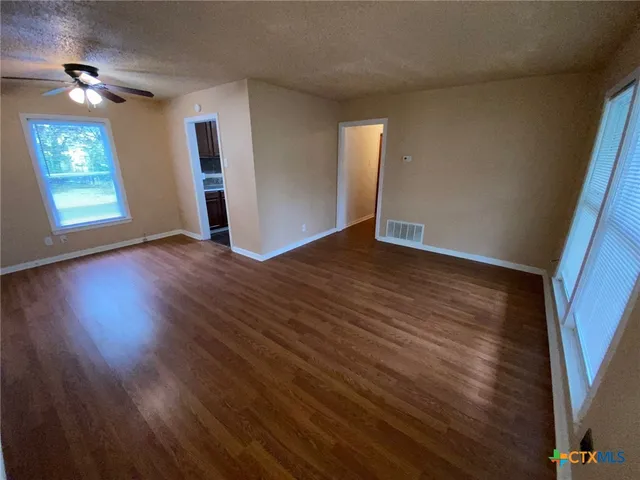 an empty room with wooden floor and windows
